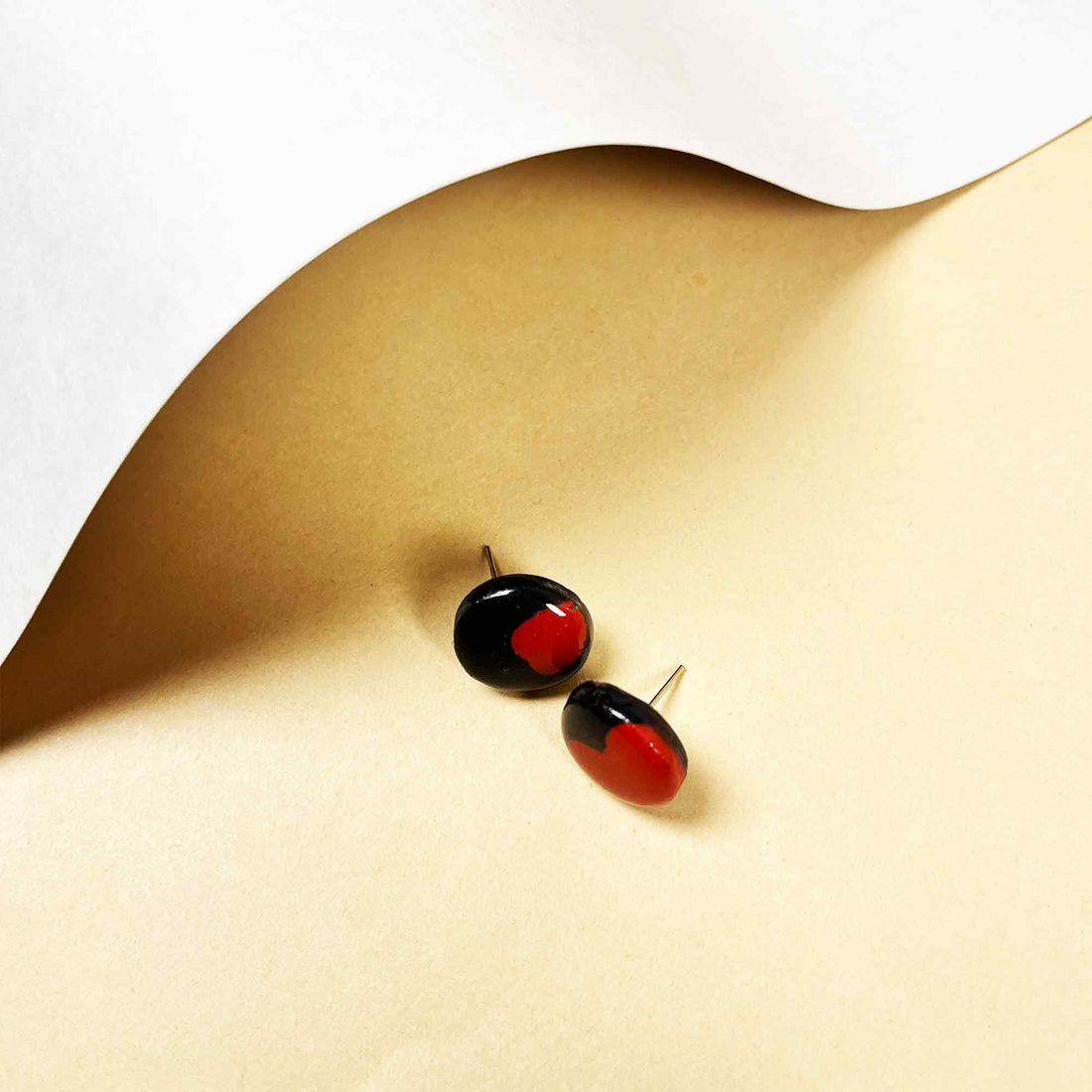 Red and black round clay earrings on card