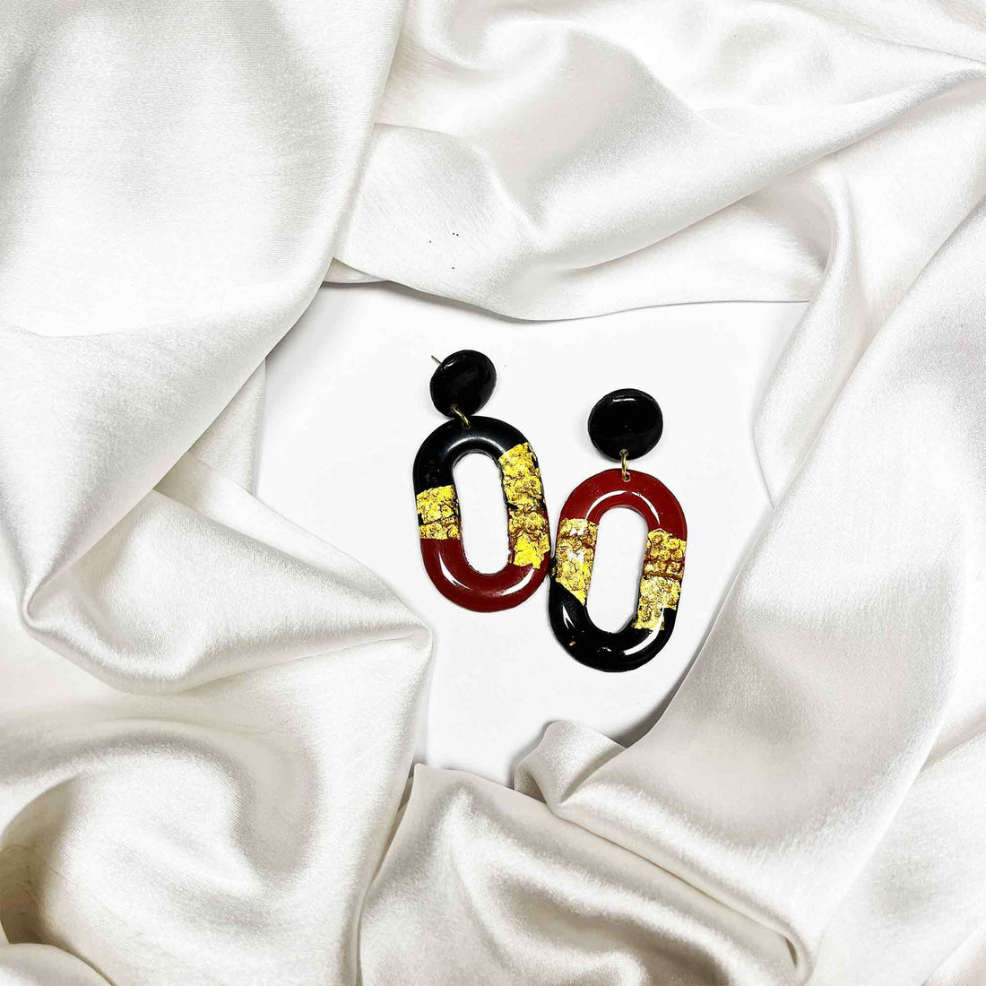 Red and black clay earrings on white satin